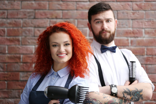 Two professional hairdresser on brick wall background