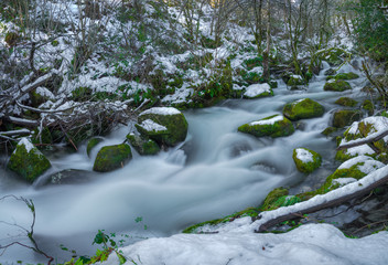 snowy river with mossy rocks
