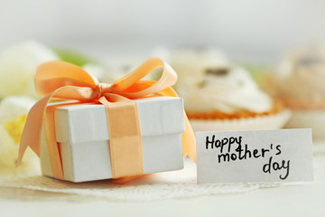 A small present with Happy Mother's day greeting card on a white table, close up