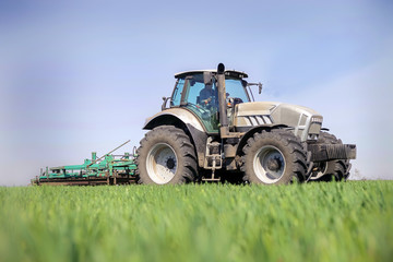 tractor operates on horizon line green field on foreground