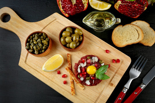Beef tartare served on a wooden board, close up
