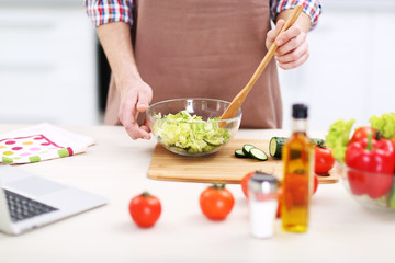 Obraz na płótnie Canvas Man cooking vegetable salad in kitchen