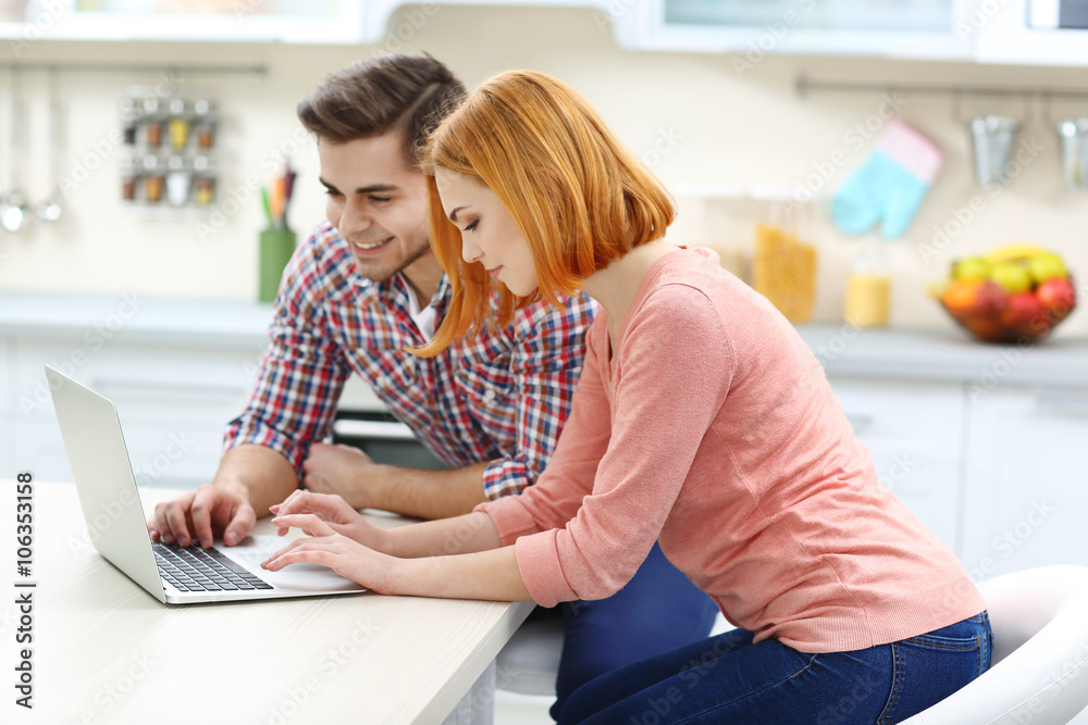 Canvas Prints Young couple using laptop on the kitchen