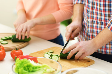 Obraz na płótnie Canvas Happy couple cooking salad on the kitchen, close up