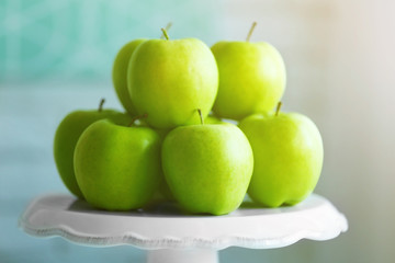 Ripe green apples on a stand in kitchen