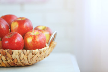 Ripe red apples in wicker basket on a kitchen table