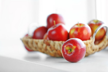 Ripe red apples in a wicker basket on windowsill