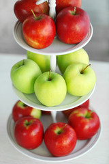 Ripe red and green apples on a stand in kitchen