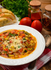 Minestrone- italian soup with vegetables on brown wooden table.