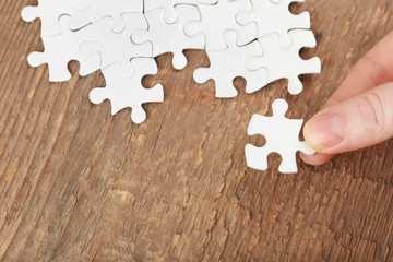 Woman playing with jigsaw puzzle on wooden table