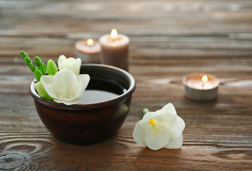 Obraz na płótnie Canvas Beautiful flower in the bowl with water and candles on wooden background