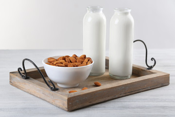 Bottles with milk and almond nuts on wooden tray