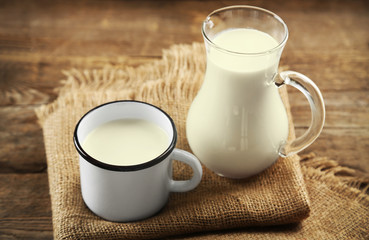 Jug and cup of milk on wooden table