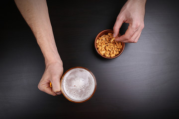 Fototapeta premium Male hand holding glass of beer on dark background
