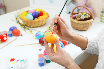 Female hands painting Easter egg at table indoors