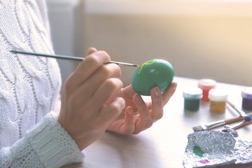 Female hands painting Easter eggs at table indoors