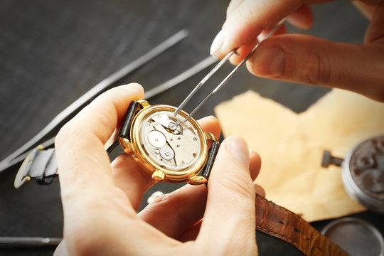 Watchmaker hands repairing mechanism of old watch closeup
