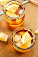 Jar of ice lemon tea with straw on wooden table