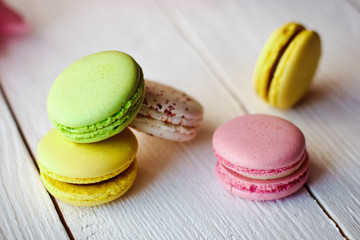 A beautiful bouquet of pink tulips with colorful macaroons on white wooden background
