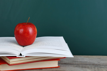 Few books with red apple on table