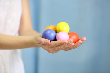 Female hands holding Easter eggs on a blue curtain background