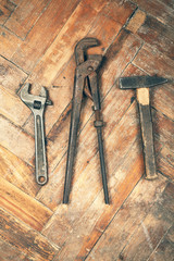 Set of adjustable spanner, pipe wrench and hammer on wooden floo