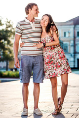 Fototapeta na wymiar The guy embraces his girlfriend during a walk in the fresh air