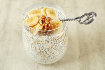 Chia seeds pudding with banana and hazelnut on grey textured background