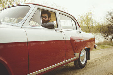 Obraz na płótnie Canvas Man with beard driving a retro car