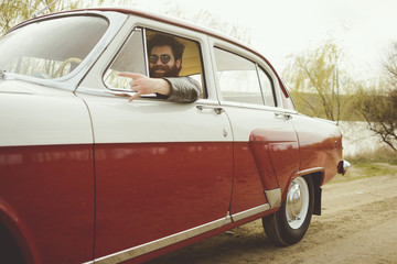 Man with beard driving a retro car