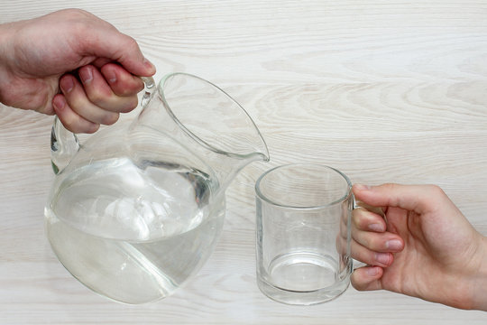 Need For Clean Water/hand With A Jug Of Water And Hand With Empty Glass