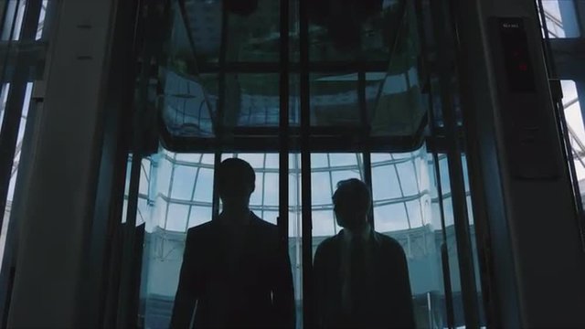 Two men emerge from the glass elevator