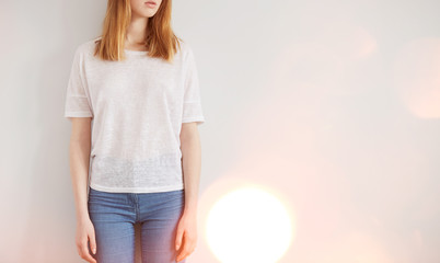 Woman wearing white blank t-shirt  standing on the background of a wall, flare light
