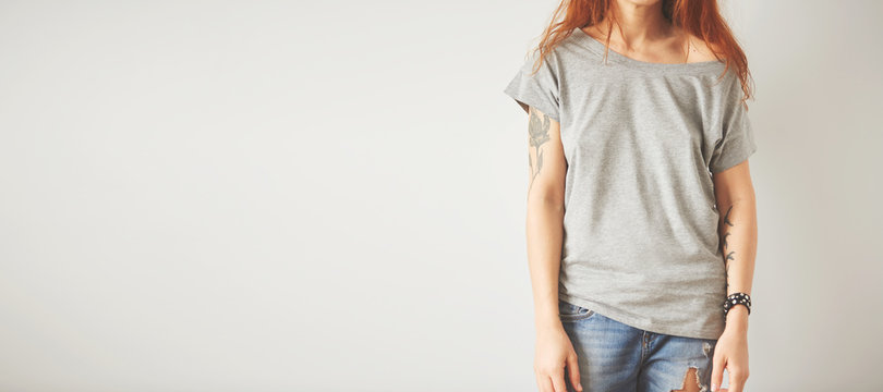 Young girl wearing grey blank t-shirt and blue jeans. Concrete wall background with copy space for your text message or promotional content
