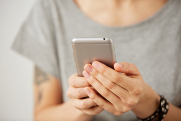 Cropped shot view of a woman's hands holding mobile phone, young female person chatting on cell telephone during work break.