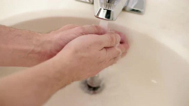 Washing hands with a bar of white soap under running water from a tap.  Slow motion, recorded 180fps.