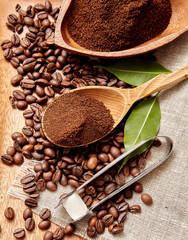 Natural ground coffee heap in a wooden spoon on a background of coffee beans