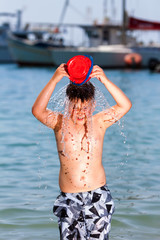 little boy in blue sea and splash water on head