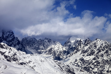 Snowy rocks in clouds at sunny day