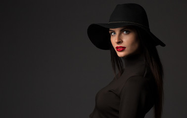 Fashion portrait of young beautiful woman model in casual wear. Black boots, hat and black dress. Copy space. 