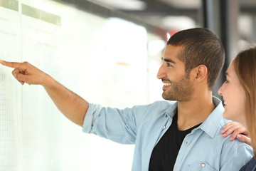 Arab man and friend consulting schedule in a station