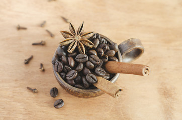 Cup with coffee beans, cinnamon sticks and star anise on a wooden table. Selective focus.