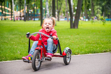 Little girl in amusement park riding on tricycle