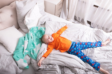 Ein kleiner Junge in einer Pyjama liegt auf dem Bett