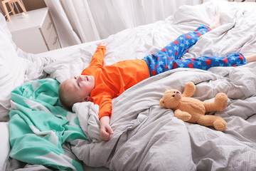 Ein kleiner Junge in einer Pyjama liegt auf dem Bett © ajlatan