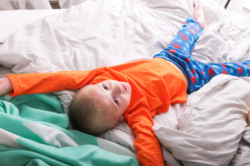 Obraz na płótnie Canvas Ein kleiner Junge in Pyjama hüpft auf dem Bett