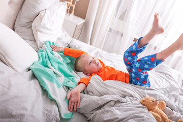 Ein kleiner Junge in Pyjama hüpft auf dem Bett