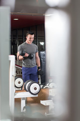 Handsome gym man lifting heavy free weights