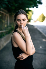 portrait of sexy young Fashion stylish woman girl model in beautiful black dress with gold necklace on the city street. Fashion trends. Outdoor summer portrait of young classy woman