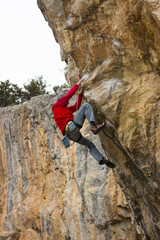 Young male climber hanging on a cliff with a rope.